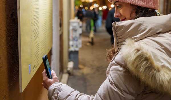 Woman scanning QR code outside restaurant 