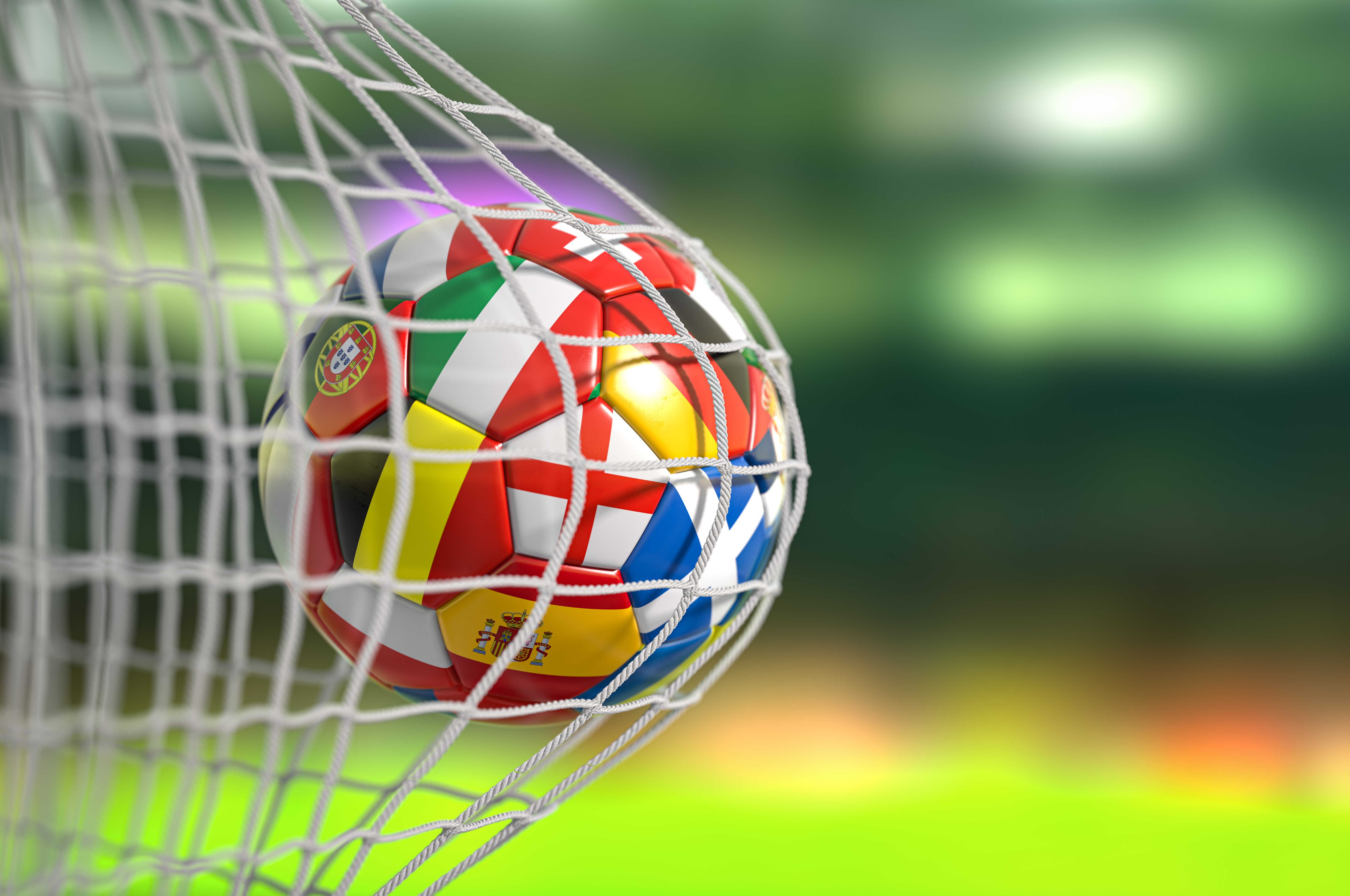 A football featuring flags of the world hit the back of a football net 